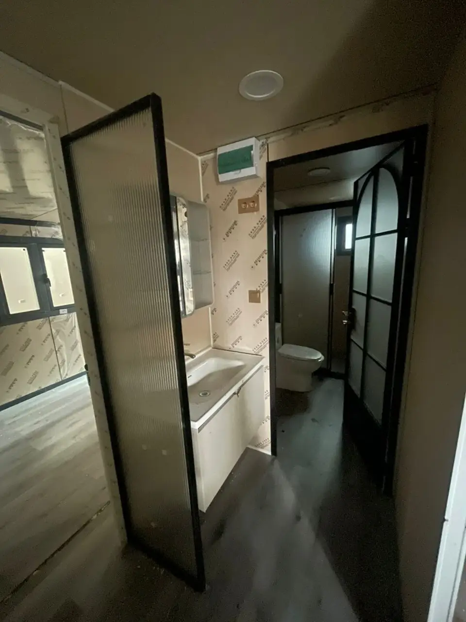 Narrow modular-home bathroom and vanity area with black-framed interior doors