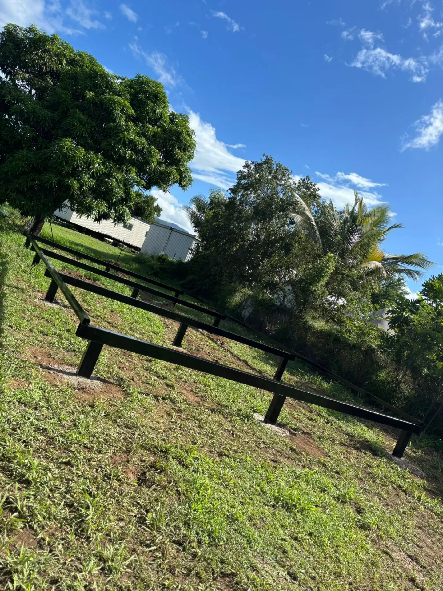 Steel foundation beams on a tropical lot with a modular building in the background