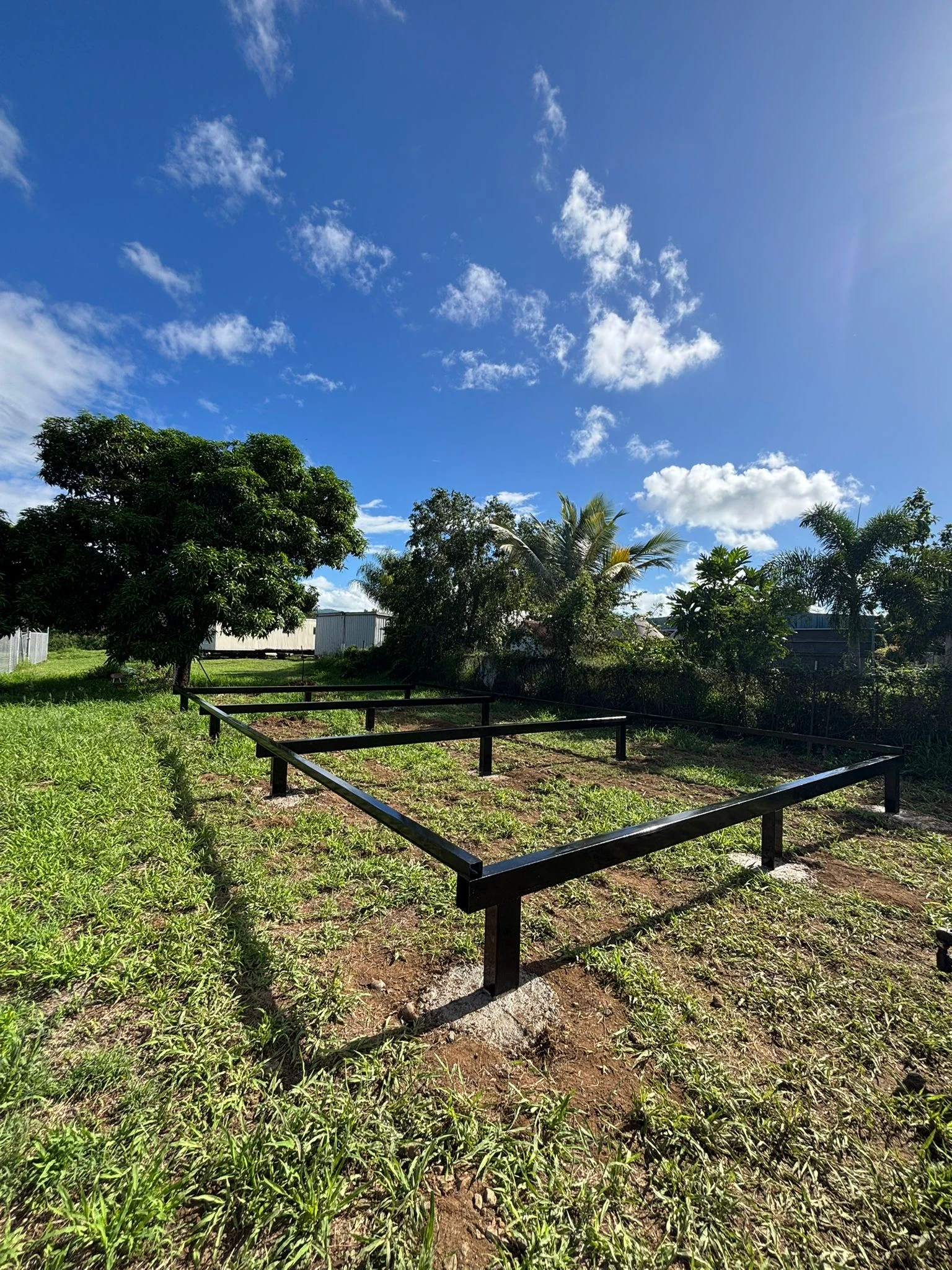 Steel foundation frame on a green property beneath a bright sky