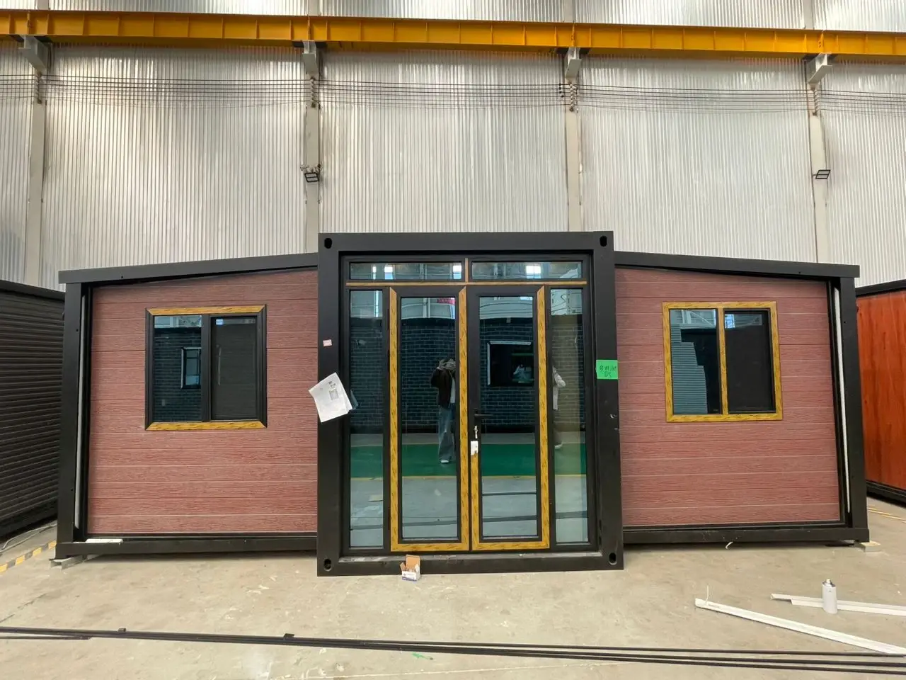 Front view of a brown modular unit with black framing and large glass doors in a factory