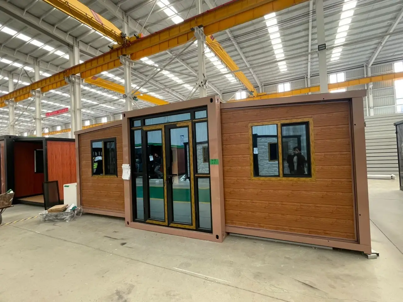 Brown wood-look modular unit with black framing inside a manufacturing warehouse