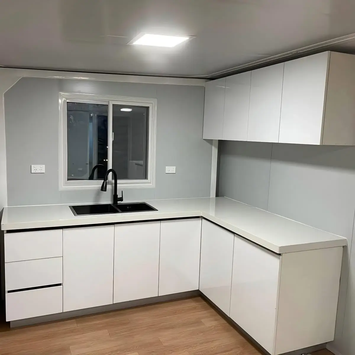 Finished white L-shaped modular-home kitchen with a black sink and faucet
