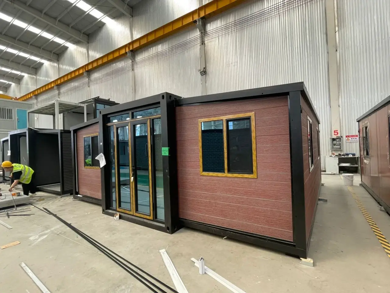 Brown modular unit inside a factory with an assembly worker nearby