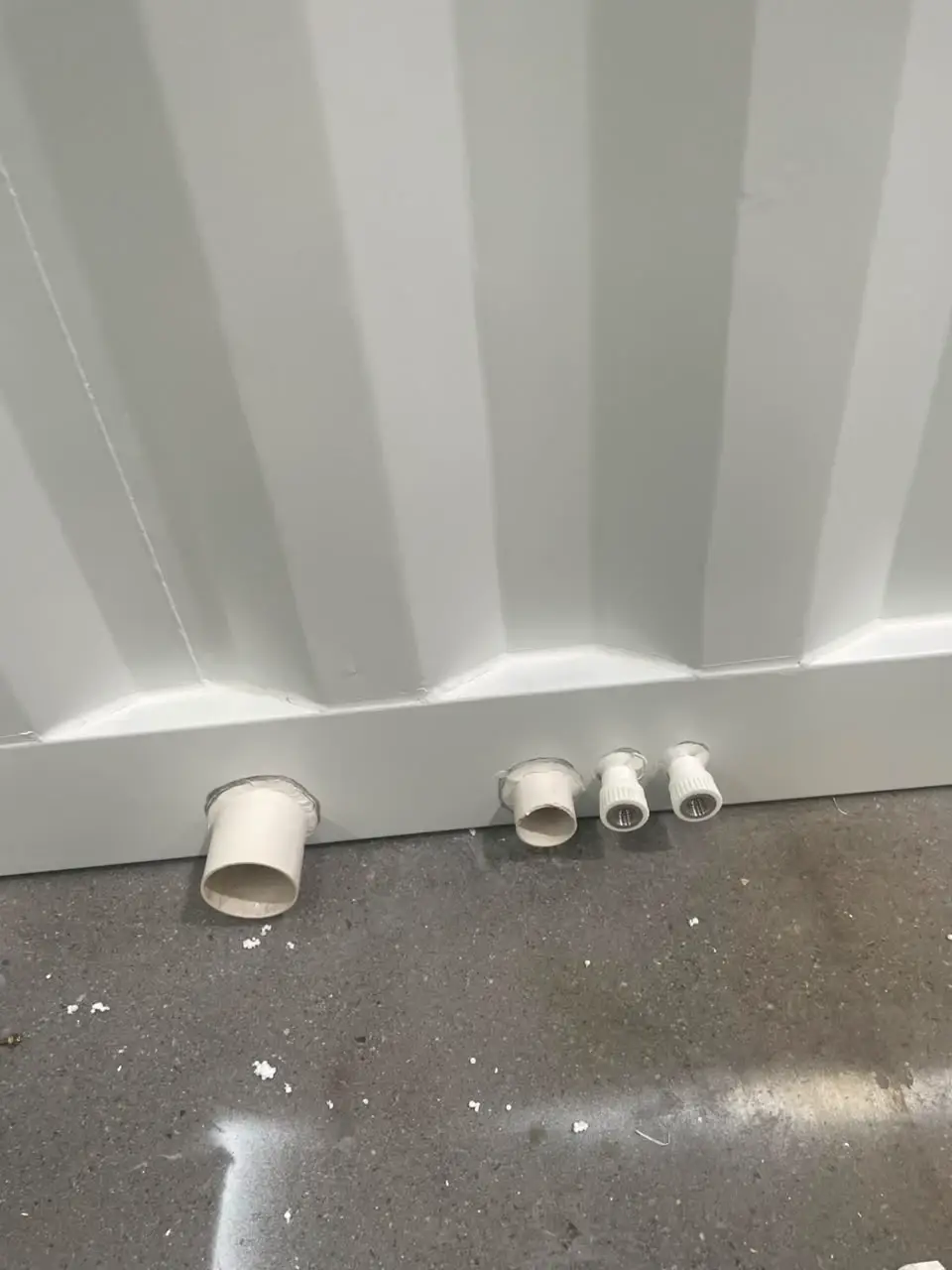Close view of four utility pipe openings through a corrugated modular wall