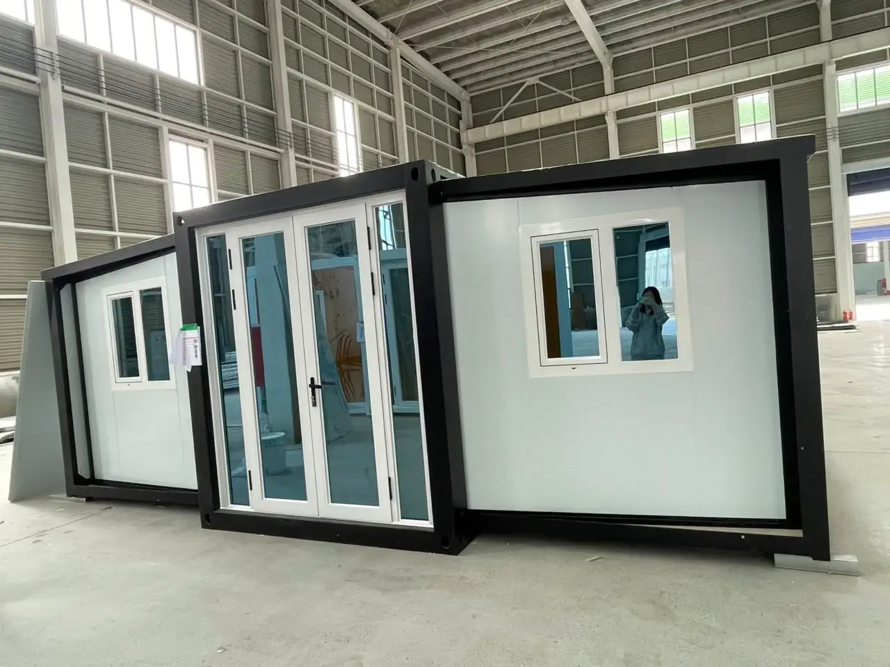 White expandable modular unit with black framing and a central glass entrance
