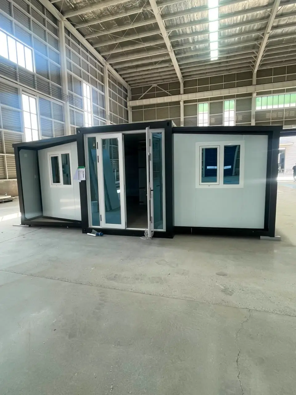 White expandable modular unit with black framing and open glass entrance doors
