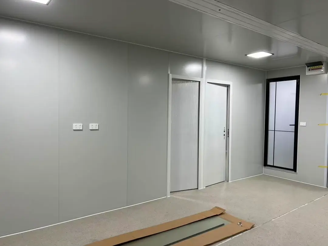 Unfinished gray modular interior with doors, windows, outlets, and a boxed glass panel