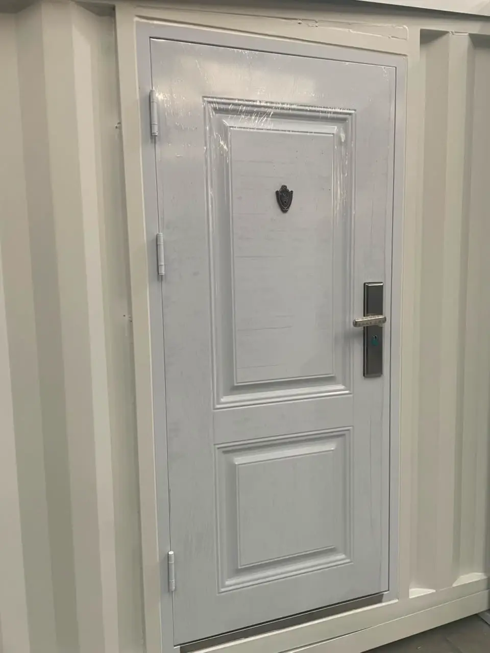 Close view of a white paneled exterior door with an electronic lock in a modular wall