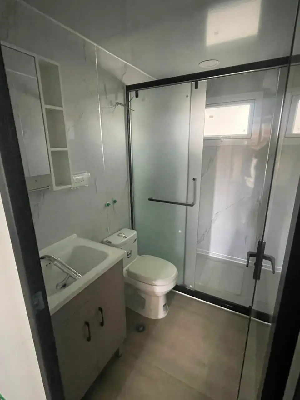 Compact modular-home bathroom with a vanity, toilet, and glass shower enclosure